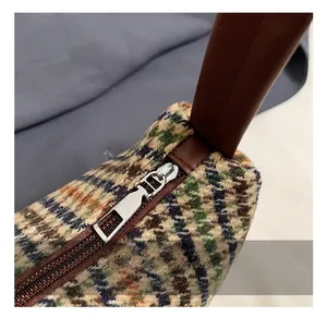 Detail of silver metal zipper and brown leather trim on vintage plaid tweed handbag
