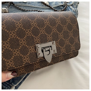 Close-up of vintage brown crossbody bag with clover pattern and metallic shield clasp