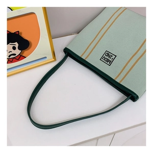 Close-up of mint green knitted tote bag with yellow stripes and dark green leather strap