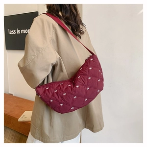 Makro-Detail der weinroten gesteppten Cloud-Tasche mit weißer Schleifenstickerei
