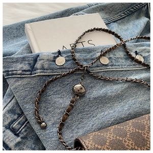 Detail of a leopard print bag featuring a gold chain strap with a round metal ball charm