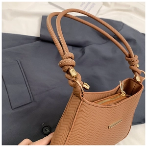 Detail shot of caramel shoulder bag with wave pattern texture and gold hardware zipper