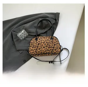 Detailed view of leopard print crossbody bag showing its compact size next to a phone