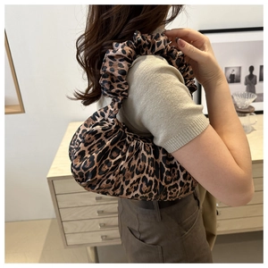 Detail of leopard print crescent bag featuring unique ruched handle and fabric texture