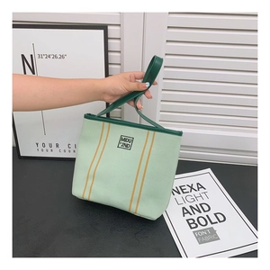 Detail of light green canvas tote bag with dark green straps and yellow stripe accents