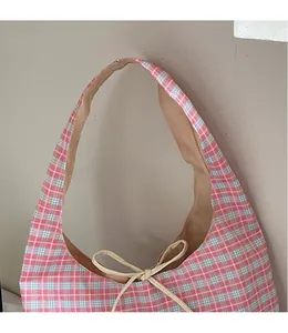 Detail of red and white checkered canvas tote bag with a beige bow drawstring closure
