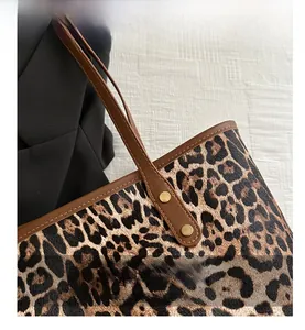 Detail of leopard print tote bag featuring brown leather trim and gold metal rivets