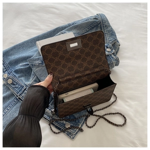 Macro view of the interior space and metal chain strap of the brown vintage flap bag