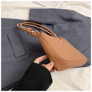 Detail view of brown shoulder bag with unique ripple texture and twisted rope handle