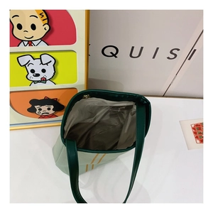 Detailed interior view of striped canvas tote bag showing green leather handles and lining