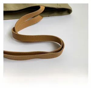 Detail of durable brown leather shoulder strap with double stitching on canvas tote bag