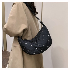 Detail der schwarzen Stepptasche mit weißen Bogenschleifen und gepolsterter Hobo-Textur