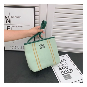 Detail of mint green canvas tote with yellow stripes and dark green trim handles