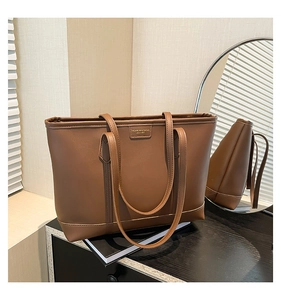 Detailed view of brown leather tote bag with embossed fashion logo and mirror reflection