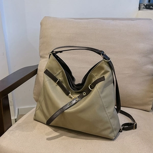 Olive green nylon tote bag with brown leather straps and gold metal clasp on sofa
