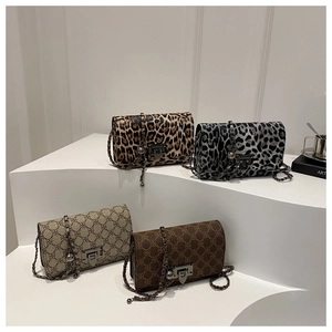 Detailed view of four vintage leopard print crossbody bags with chain straps on a white stand
