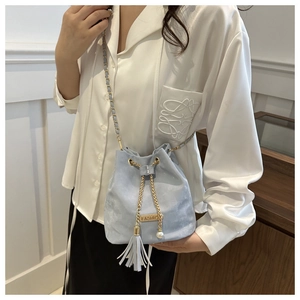 Detail of light blue velvet bucket bag featuring gold chain and pearl tassel charm