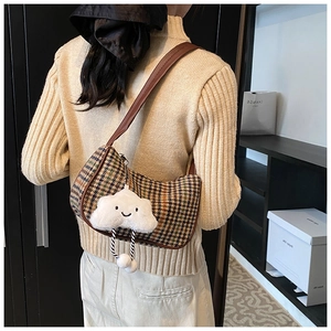 Detail of vintage houndstooth hobo bag with leather strap and plush cloud charm on model