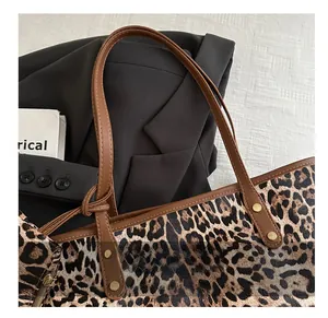 Detail of comfortable brown leather shoulder strap and metal rivets on leopard print tote