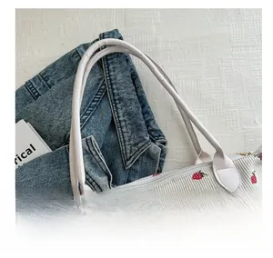 Detail of strawberry print corduroy tote bag with durable white faux leather handles