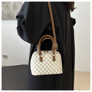 Detail showing vintage triomphe pattern on beige mini shell bag with brown leather strap