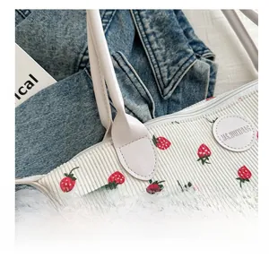 Close-up of white corduroy tote bag featuring strawberry prints and MS.HUIXIBAG logo
