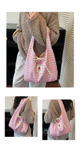 Close-up of blue and pink checkered canvas tote with decorative beige drawstring bow detail