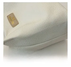 Detail of the white woven fabric texture and premium leather tag on a minimalist tote bag