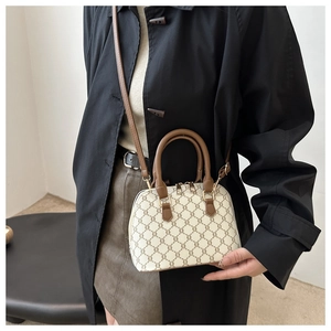 Close-up of the vintage shell bag with adjustable leather strap and triomphe pattern
