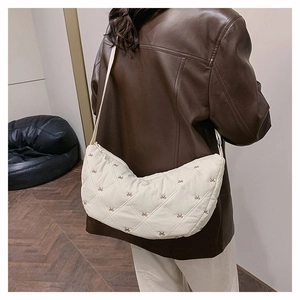 Gesteppte Halbmond-Schultertasche mit Schleifenstickerei getragen von einem Model