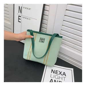 Detail of light green canvas tote bag with orange stripes and dark green handle