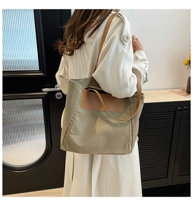 Modern canvas tote bag worn by model with brown leather straps and front pocket detail