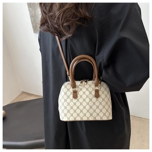 Detailed view of cream and brown monogram shell bag worn by model over black outfit