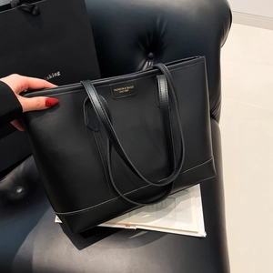 Minimalist large black faux leather tote bag with gold logo for work and commuting