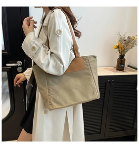 Detailed view of the large canvas tote bag with brown leather handles and decorative stitching