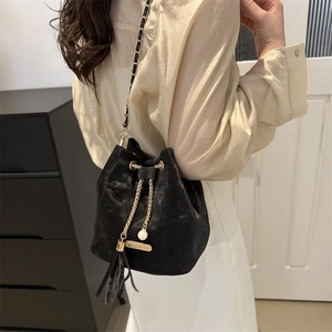 Elegant black drawstring bucket bag with gold chain strap and pearl tassel detail