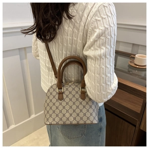 Detail of vintage patterned shell bag with brown leather handles and adjustable shoulder strap