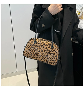 Leopard print handbag with dual handles and adjustable strap worn as a crossbody bag