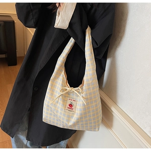 Detail of yellow and blue checkered canvas tote bag with tomato patch and drawstring closure