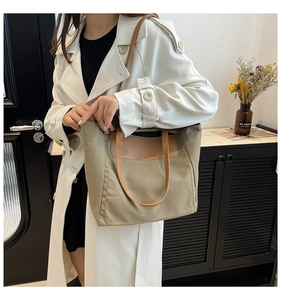Detail of khaki canvas tote with brown leather handles and decorative yellow stitching