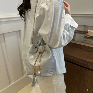Silver metallic drawstring bucket bag with gold chain strap and pearl tassel detail