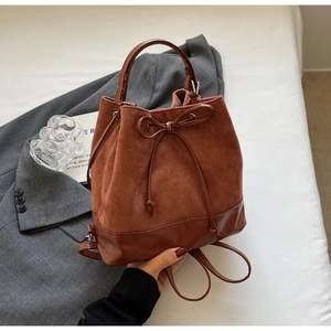 Detail of vintage brown suede bucket backpack with contrast leather trim and drawstring bow