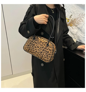 Detail of leopard print suede tote bag carried by a model in a stylish black coat