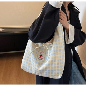 Detail of blue and yellow plaid canvas tote bag with drawstring closure and tomato patch