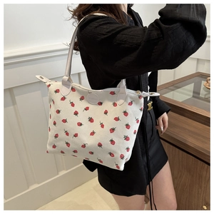 Detail of strawberry print corduroy tote bag with grey leather handles and zipper