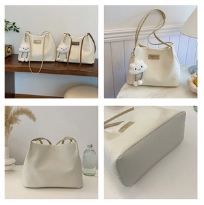 Detail of cream woven tote bag with leather straps and a plush cloud charm accessory