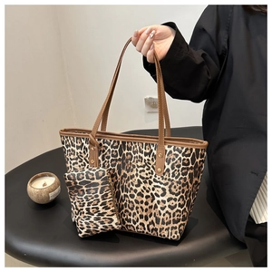 Detail view of leopard print tote bag with brown leather handles and matching pouch set