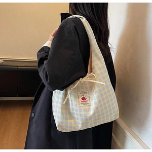 Detail of yellow and blue checkered canvas tote bag with drawstring and cute patch