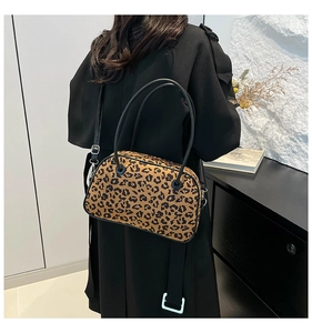 Detail view of stylish leopard print crossbody bag with black handles on a model back