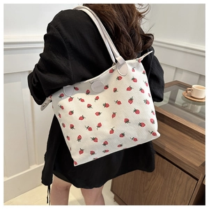 Close-up of strawberry print tote bag with striped texture and gray shoulder strap